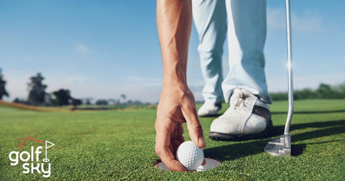 A golfer reaching into the hole to lift out a ball on a sunlit green, with the Golf Sky logo