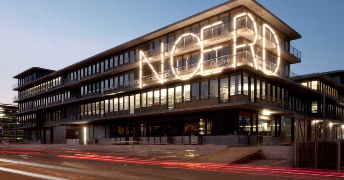 The NOERD building in Zurich at dusk, its illuminated rooftop sign lit against a blue sky