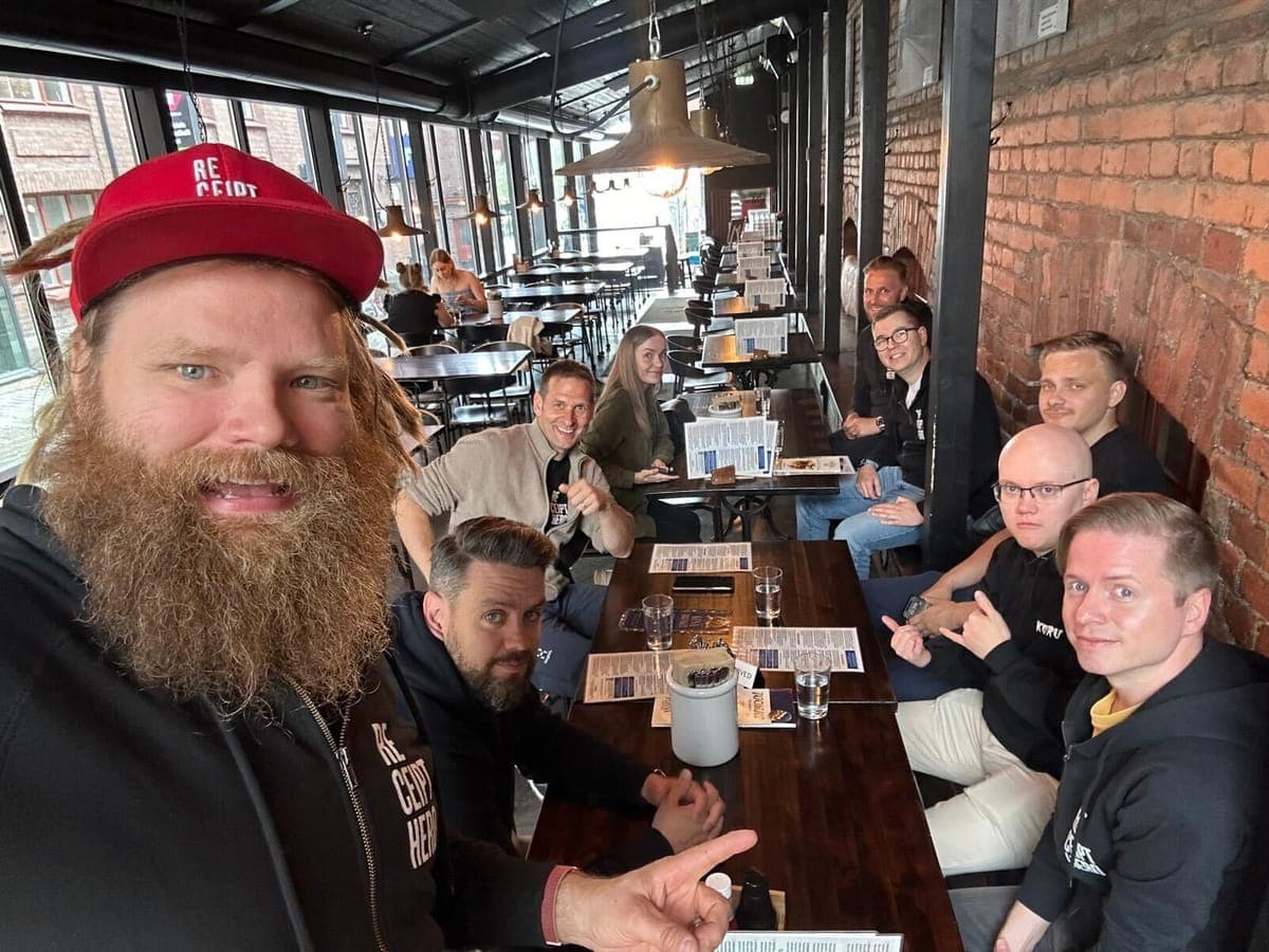 A selfie of the ReceiptHero team around a long table in a brick-walled restaurant, several in branded hoodies and a red cap