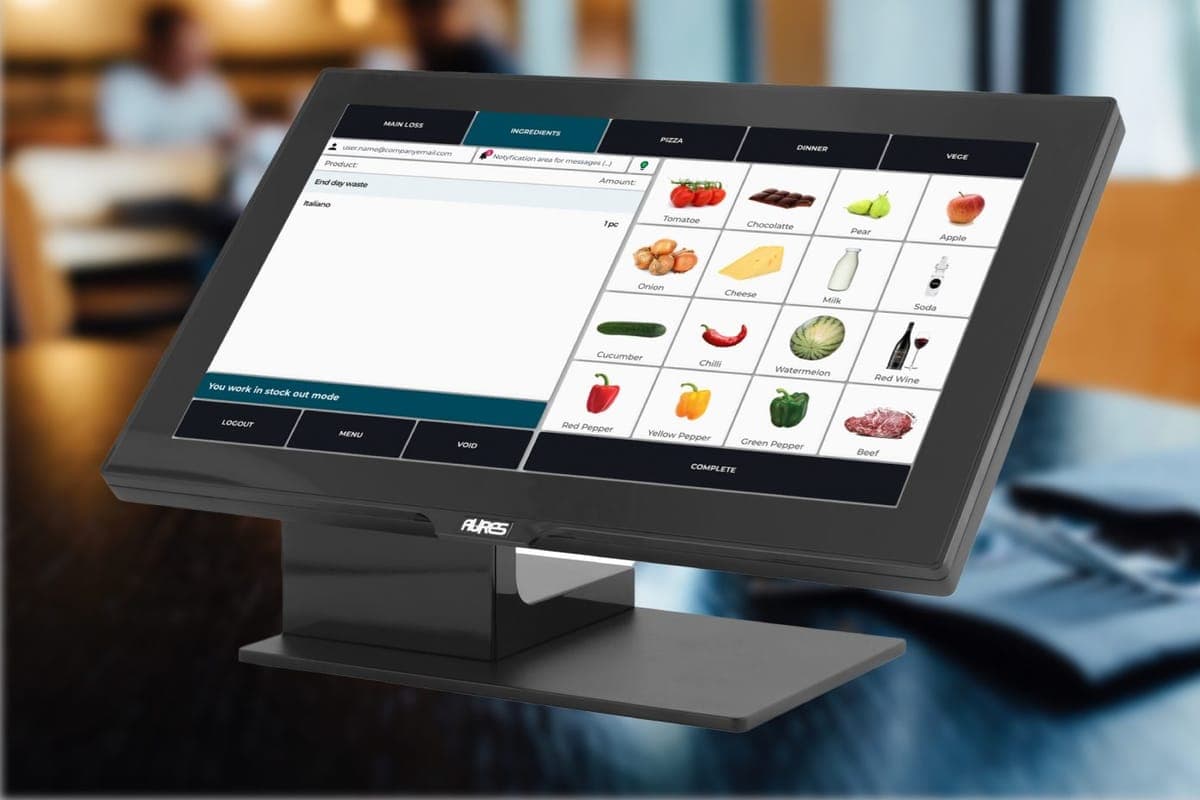 A touchscreen till showing a product grid of ingredients, with tabs for pizza, dinner and vegetarian items