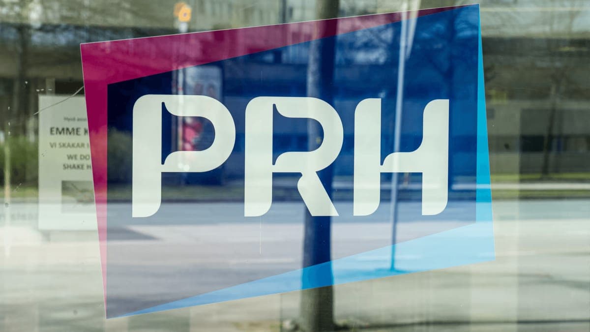 The PRH logo on the glass door of the Finnish Patent and Registration Office, the street reflected in it
