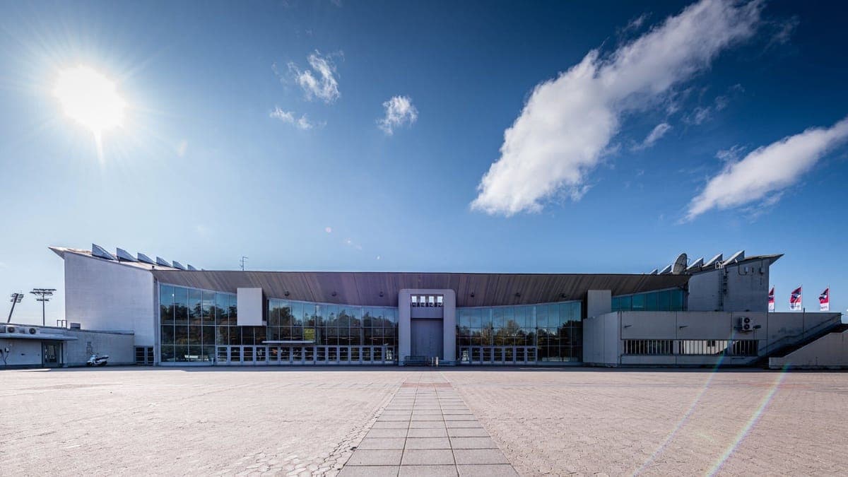 The exterior of the Helsinki Ice Hall on a clear sunny day, its glass frontage and empty forecourt