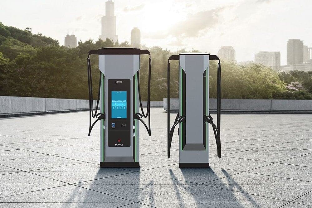 Two Siemens Sicharge EV fast chargers on a paved plaza, a city skyline behind them