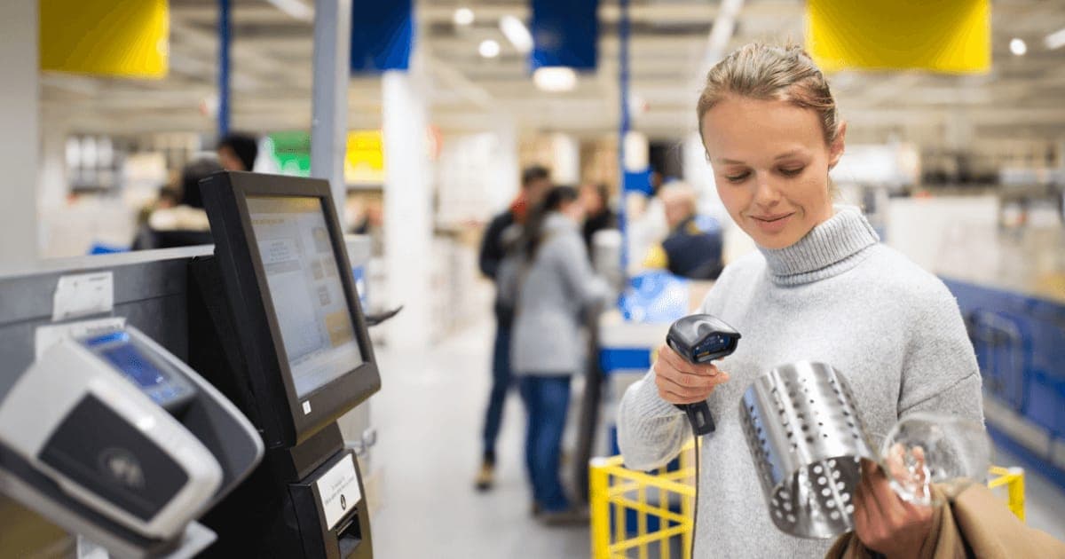 A shopper scanning a kitchen item at a self-service checkout in a furniture store