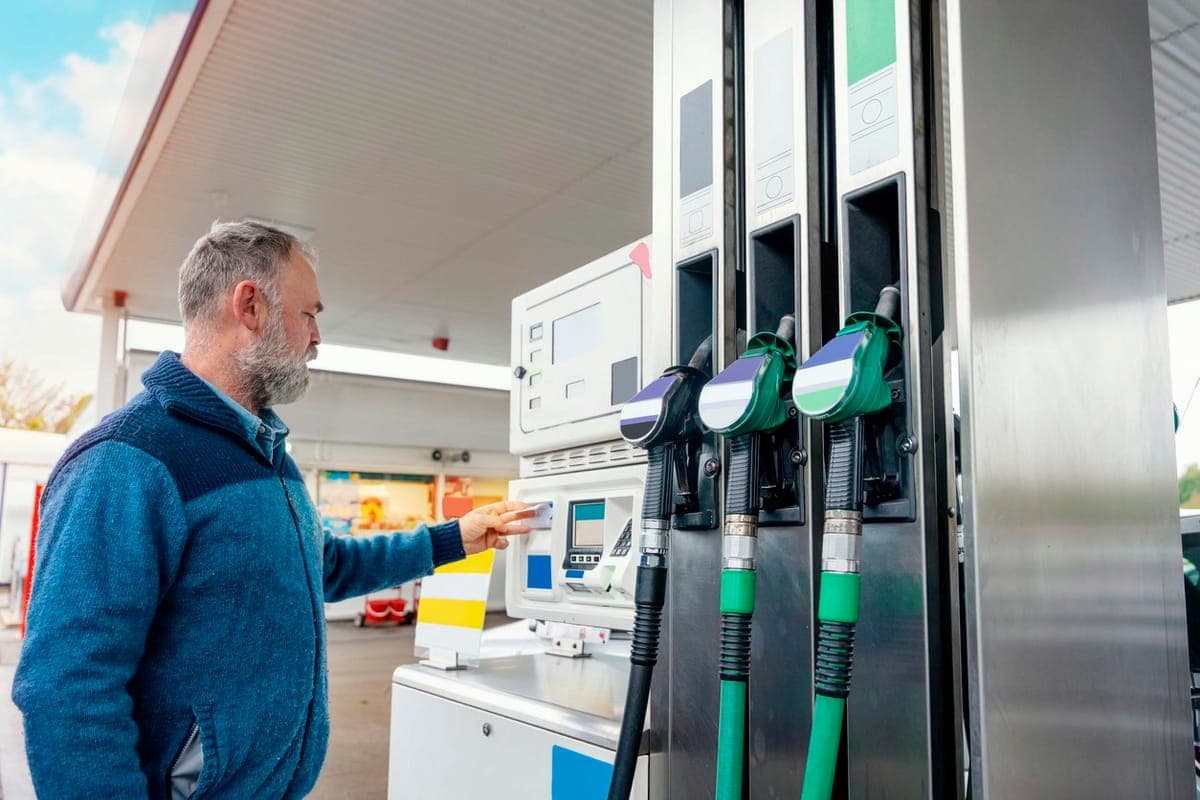 A man holding a card up to the reader on a fuel pump at a petrol station