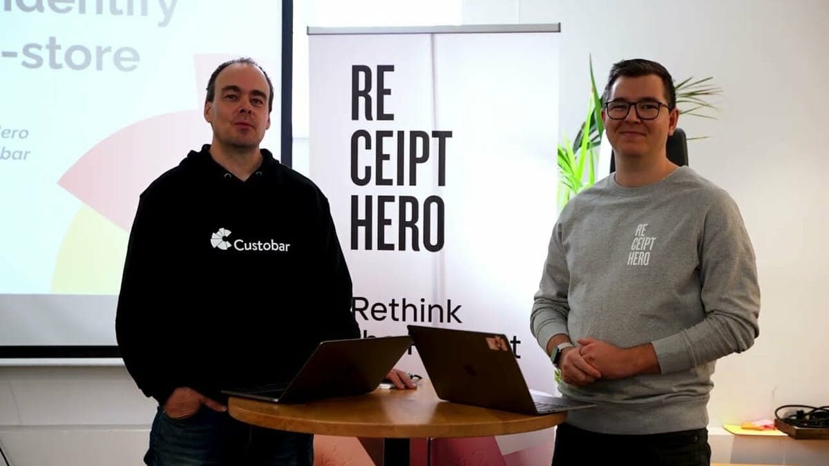 Two people in Custobar and ReceiptHero branded tops standing at laptops in front of a ReceiptHero banner